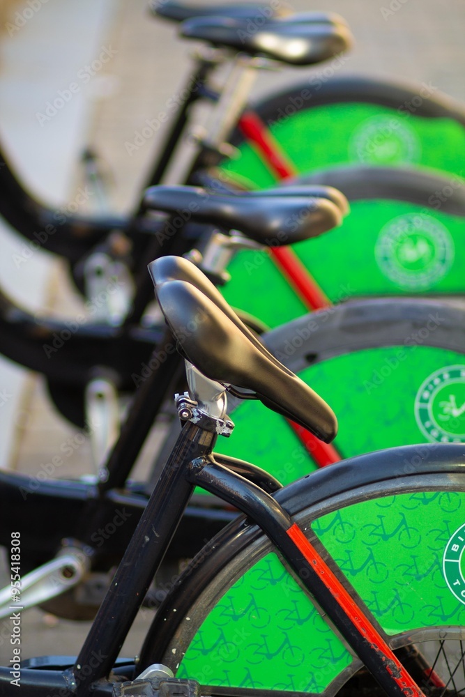 A collection of bicycles with bright green wheels sits neatly in a bike-sharing dock as the evening sun casts a warm glow, inviting riders to explore the city A collection of bicycles with bright green wheels sits neatly in a bike-sharing dock as the evening sun casts a warm glow, inviting riders to explore the city