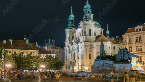 Baroque St. Nicholas' Cathedral on the Oldtown Square in Prague with monument Jan Hus illuminated at night timelapse photo