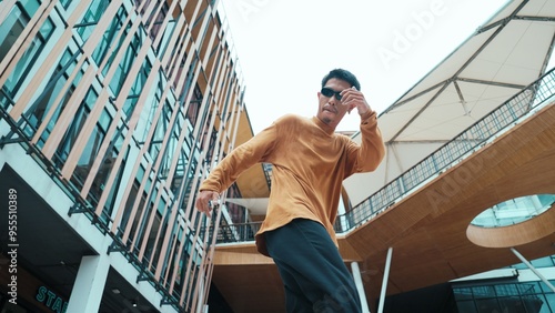 Hispanic dancer looking at camera while dancing in hip hop style. Young attractive hipster moving and dancing to music. Motion shot of break dancer perform b-boy dance Outdoor sport 2024. Hiphop.