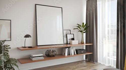 A modern living room with a white wall and home decor pieces. There's an empty mock-up black poster frame on a wooden shelf. 