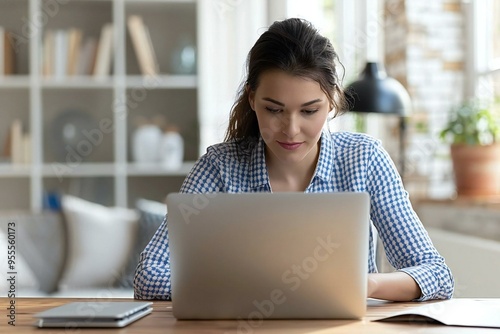 photo of a woman participating in an online E-learning interview or webinar at her desk with a laptop.