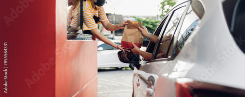 Hand Man in car receiving coffee in drive thru fast food restaurant. Staff serving takeaway order for driver in delivery window. Drive through and takeaway for buy fast food for protect covid19.