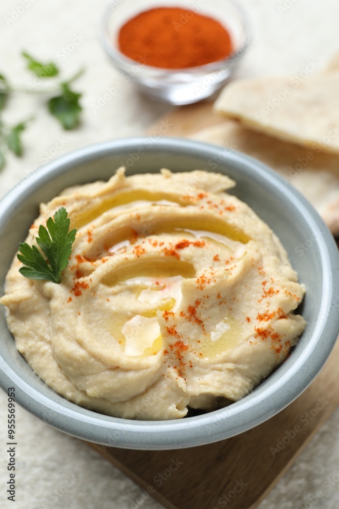 Delicious hummus with olive oil, parsley and paprika in bowl on white table, closeup Delicious hummus with olive oil, parsley and paprika in bowl on white table, closeup