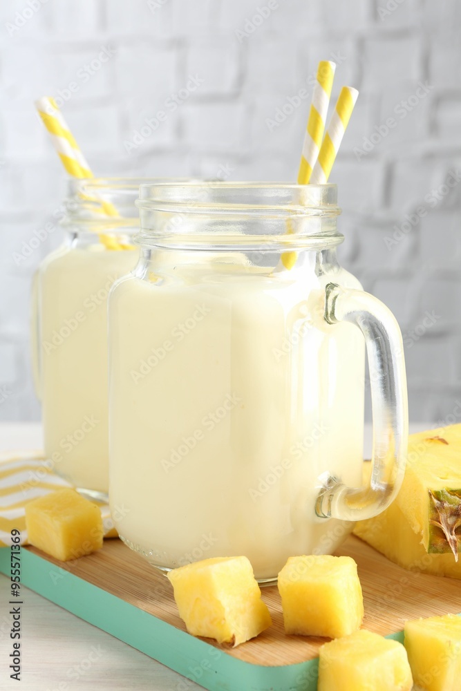 Tasty pineapple smoothie in mason jars and fresh fruit on table Tasty pineapple smoothie in mason jars and fresh fruit on table