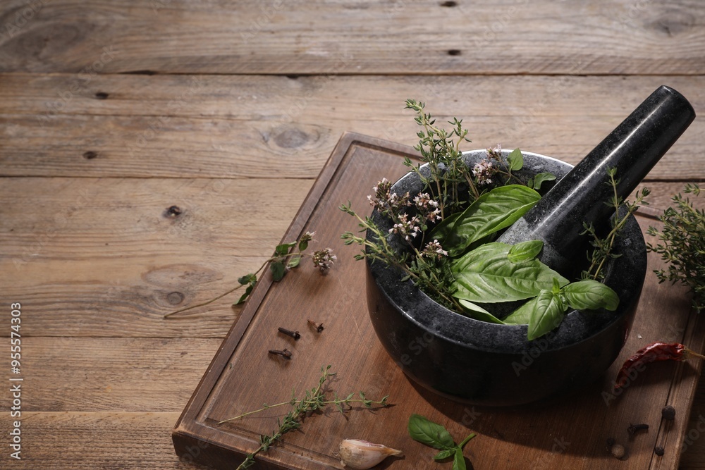 Mortar with different aromatic herbs on wooden table, space for text Mortar with different aromatic herbs on wooden table, space for text