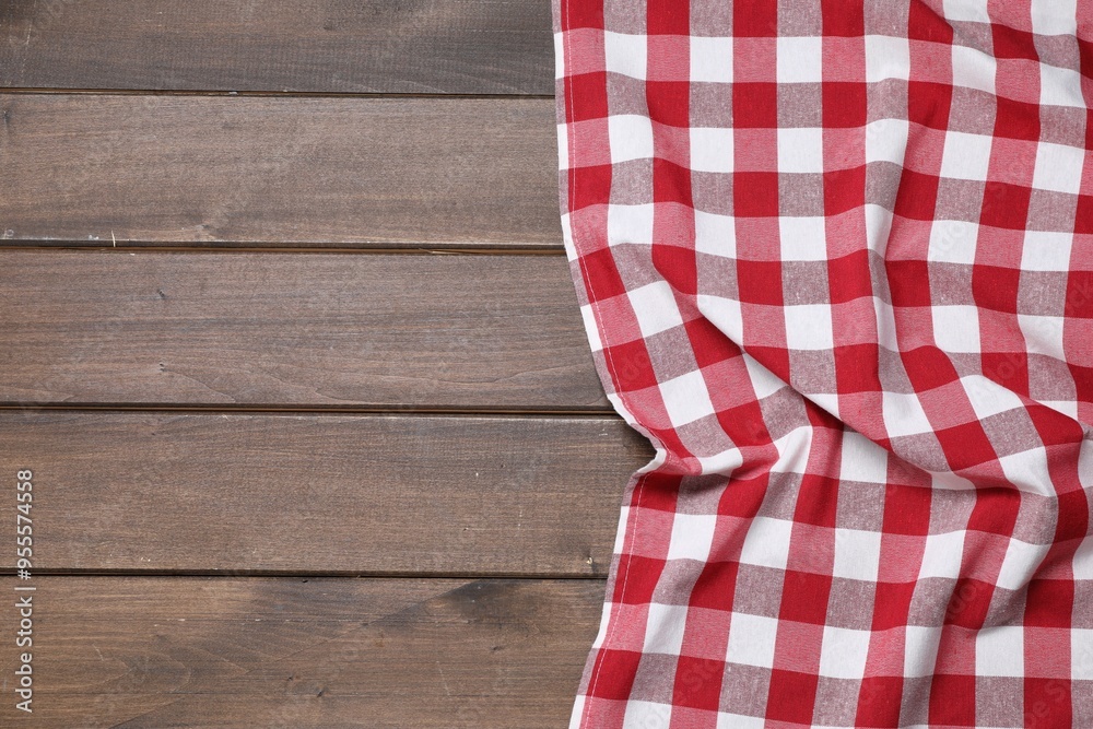 Obraz premium Crumpled tablecloth with checkered pattern on wooden table, top view. Space for text