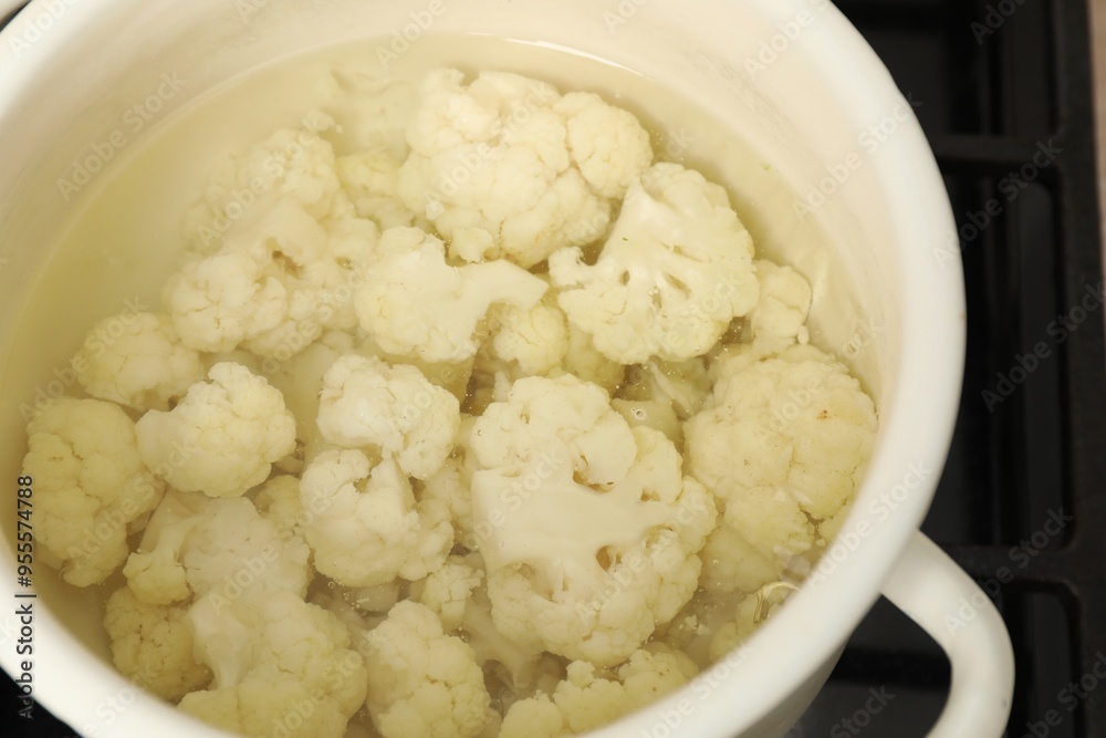 Cooking cauliflower. Florets in white pot with water on cooktop, closeup Cooking cauliflower. Florets in white pot with water on cooktop, closeup