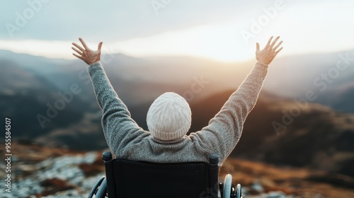 An inspirational scene showing a person in a wheelchair facing a breathtaking landscape, raising their arms towards the sky, celebrating freedom, determination, and the beauty of nature. photo