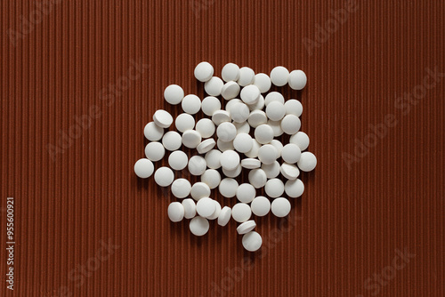 Several small white round tablets are randomly distributed across on brown textured background photo