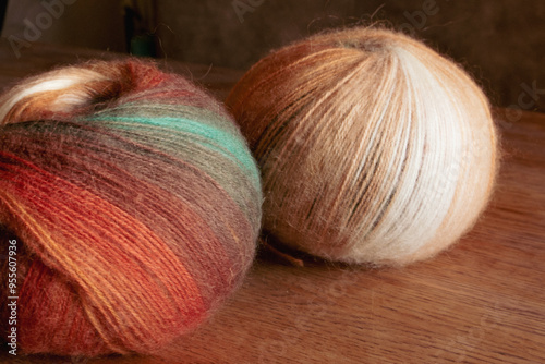 Two multi coloured yarn balls on table. Bright knitting yarn. Knitting hobby. Handicraft concept. Wool and alpaca wool threads. Autumn fashion. Needlework concept.
