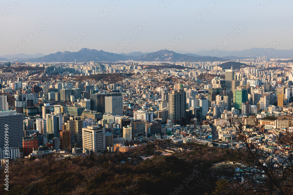 Fototapeta premium Beautiful vibrant aerial sunset view of Seoul, South Korea skyline, with mountains and sprin scenery beyond the city, seen from observation deck of Namsan Park, Gyeonggi-do province, Republic of Korea