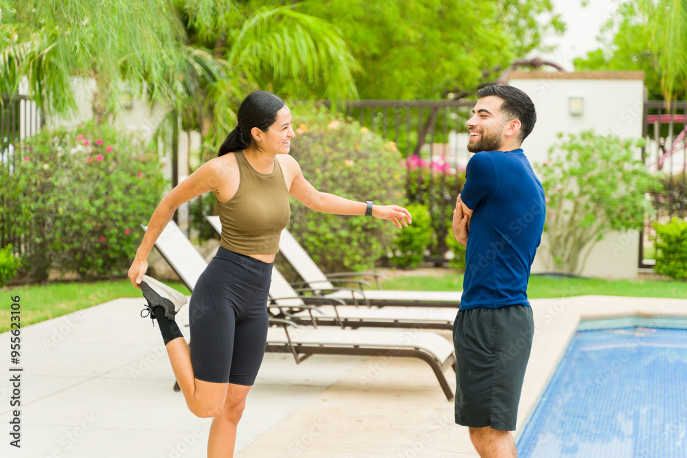 Obraz premium Happy athletic couple preparing for their workout by the pool in their backyard