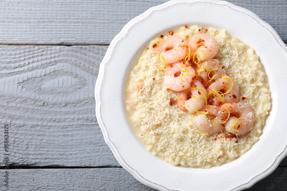 Delicious risotto with shrimps and cheese on grey wooden table, top view. Space for text Delicious risotto with shrimps and cheese on grey wooden table, top view. Space for text
