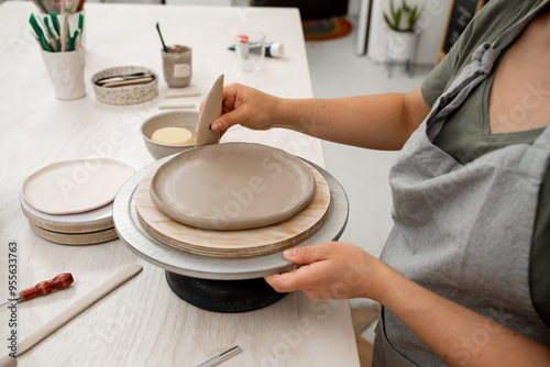 Crafting smooth angle conversion and textured ribs with a clay pottery scrapper. Girl is using a pottery scrapper to smooth the edges of a clay product. photo