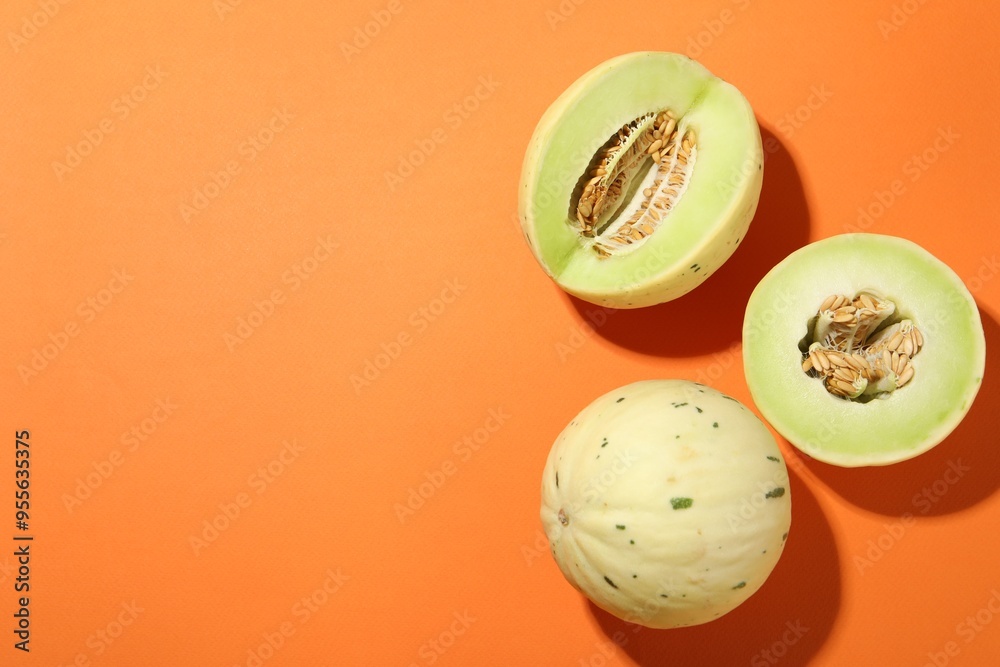 Fresh ripe honeydew melons on orange background, top view. Space for text Fresh ripe honeydew melons on orange background, top view. Space for text