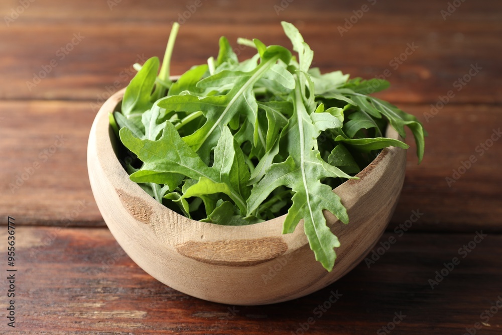 Fresh green arugula leaves in bowl on wooden table, closeup Fresh green arugula leaves in bowl on wooden table, closeup