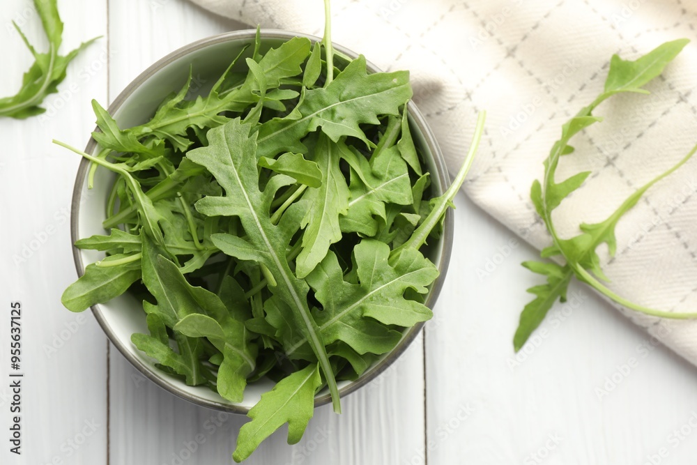 Fresh green arugula leaves in bowl on white wooden table, top view Fresh green arugula leaves in bowl on white wooden table, top view