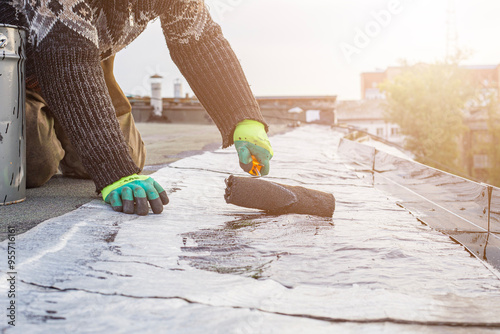 Foto a young worker treats a roof with bitumen primer before applying rolled asphalt