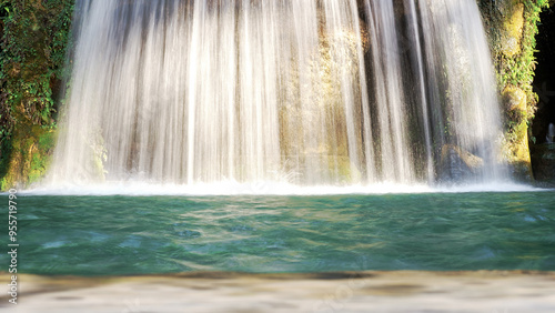 Sunlight Illuminates The Water Of A Beautiful Waterfall Cascading Into A Tranquil Turquoise Pool