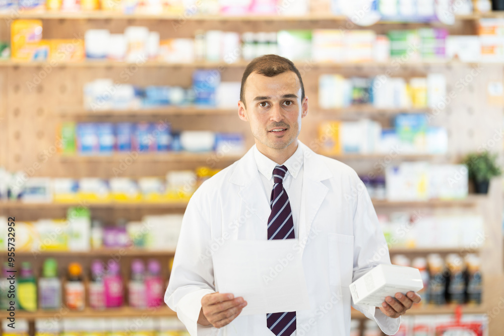 Fototapeta premium At pharmacy, male pharmacist received paper with medical appointment, reads document, remembers treatment regimen, thinks about selling suitable medicine