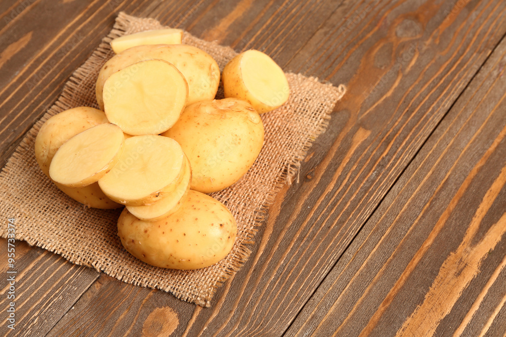 Raw baby potatoes and slices on wooden background