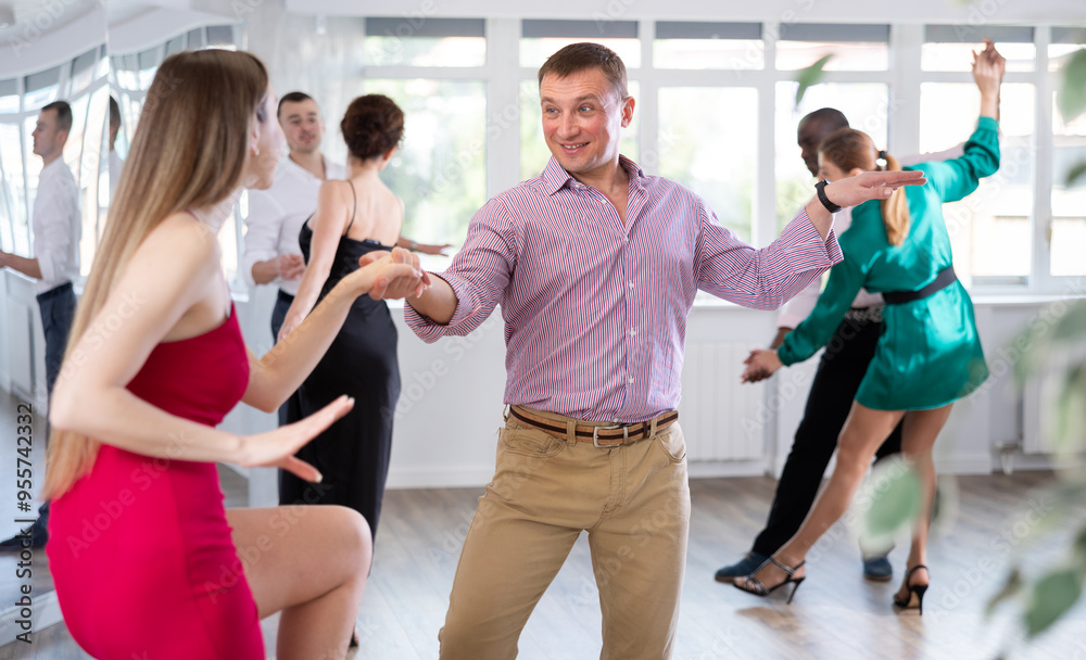 Obraz premium Positive woman and man dancing foxtrot in pair during group dance party