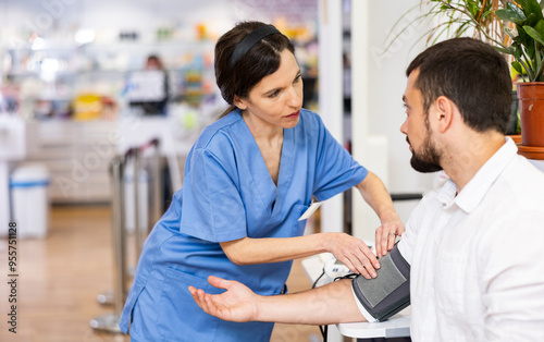 Nurce measuring man's blood pressure in drugstore. Diagnostic procedure in pharmacy. photo