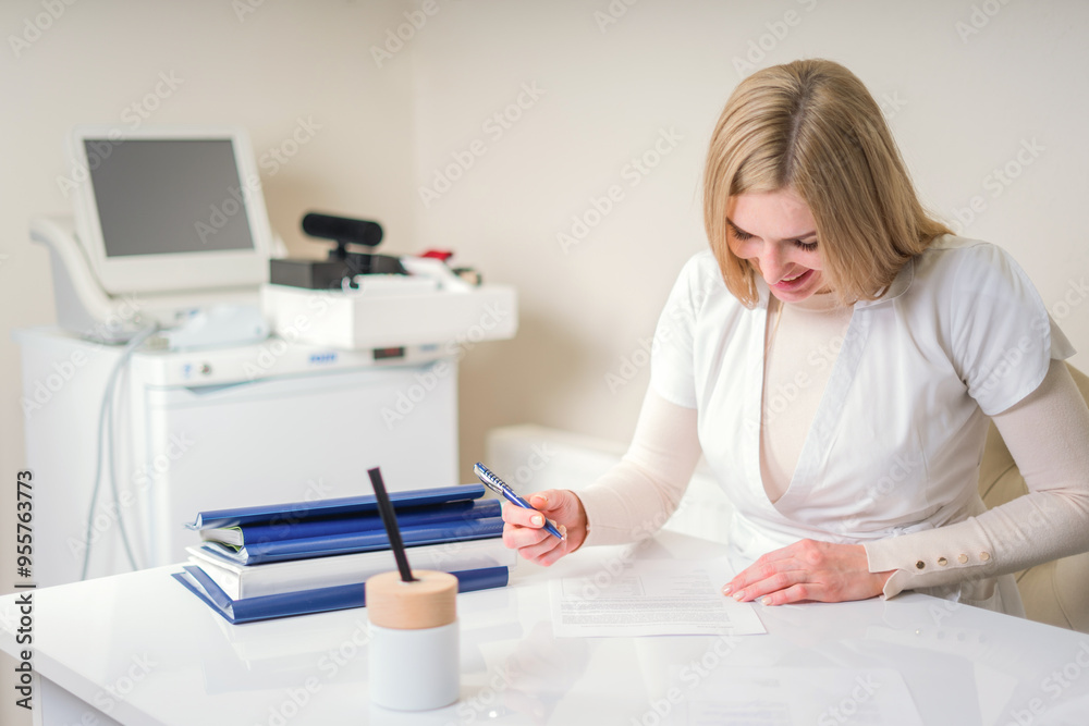 Female young doctor writing sitting at her office with medical equipment on a background. Healthcare and medical concept Female young doctor writing sitting at her office with medical equipment on a background. Healthcare and medical concept