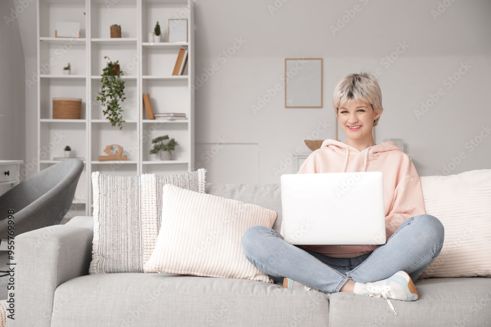 Portrait of beautiful young woman with laptop sitting on sofa at home Portrait of beautiful young woman with laptop sitting on sofa at home