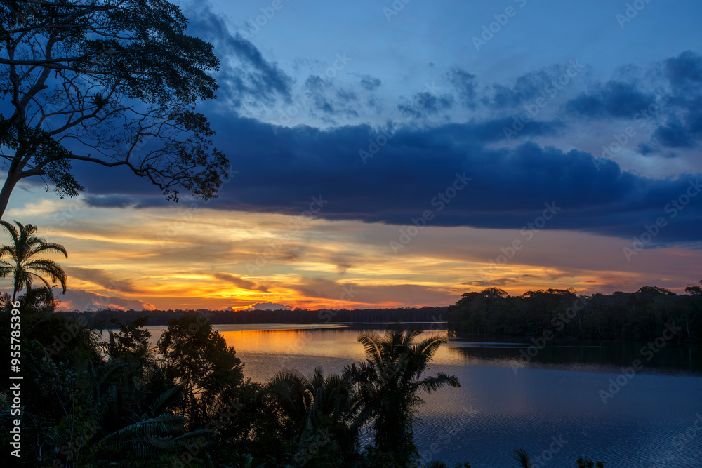 Naklejka premium Beautiful sunset over a calm lake with tree silhouettes