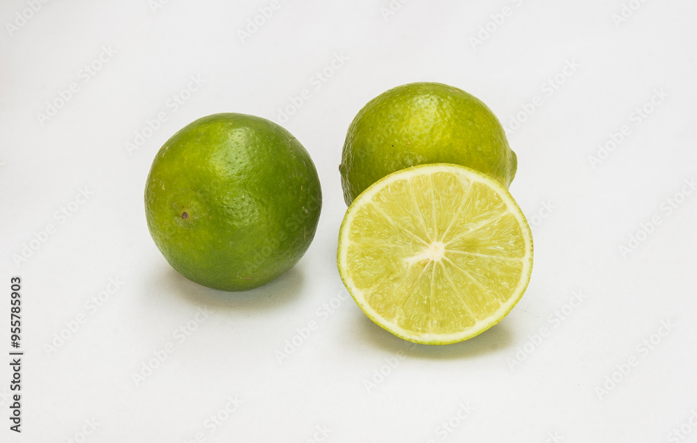Fresh green limes with one cut open to show inside pulp Fresh green limes with one cut open to show inside pulp