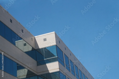 Top of White Brick Office Buidling with Blue Windows Against Blue Sky