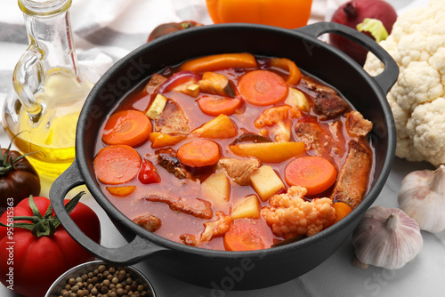 Tasty homemade stew with vegetables on white tiled table, closeup