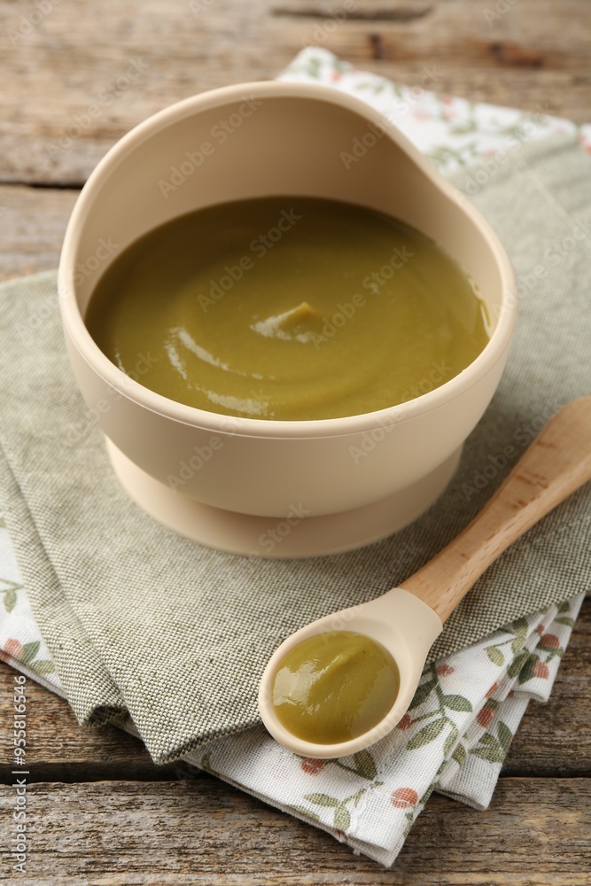 Delicious baby food in bowl with spoon on wooden table Delicious baby food in bowl with spoon on wooden table
