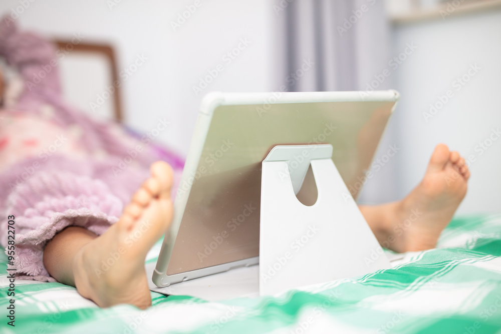 Little girl watching iPad on bed