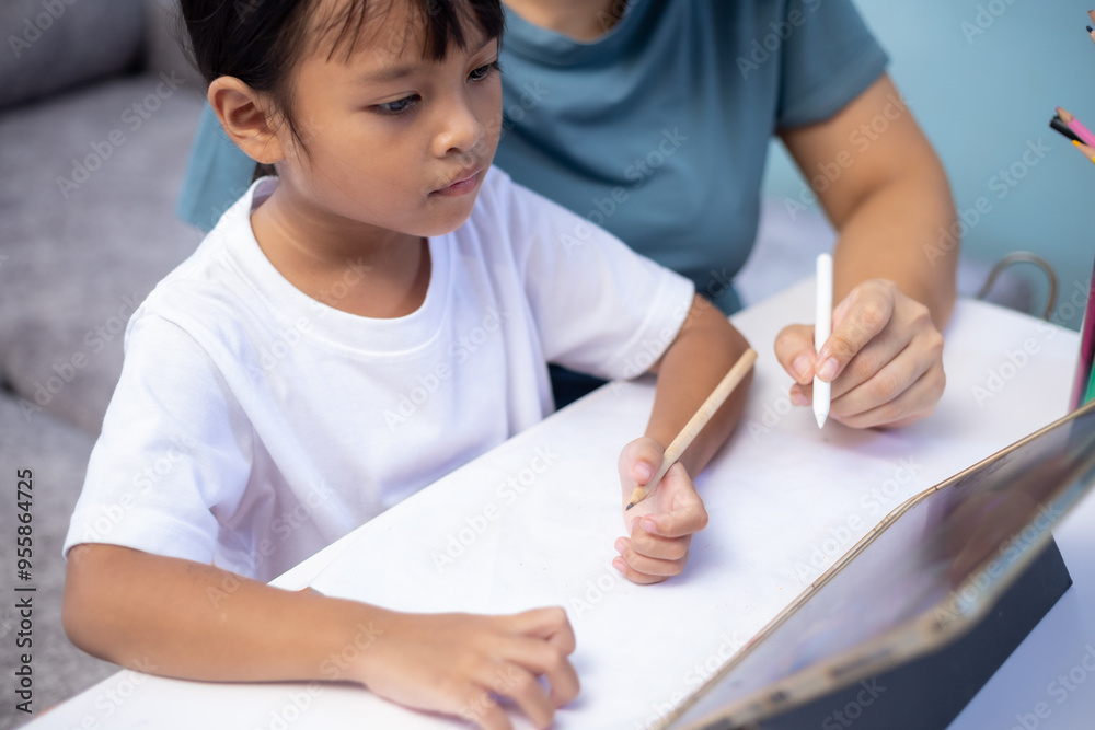 A woman and a child are sitting at a table with a tablet in front of them A woman and a child are sitting at a table with a tablet in front of them