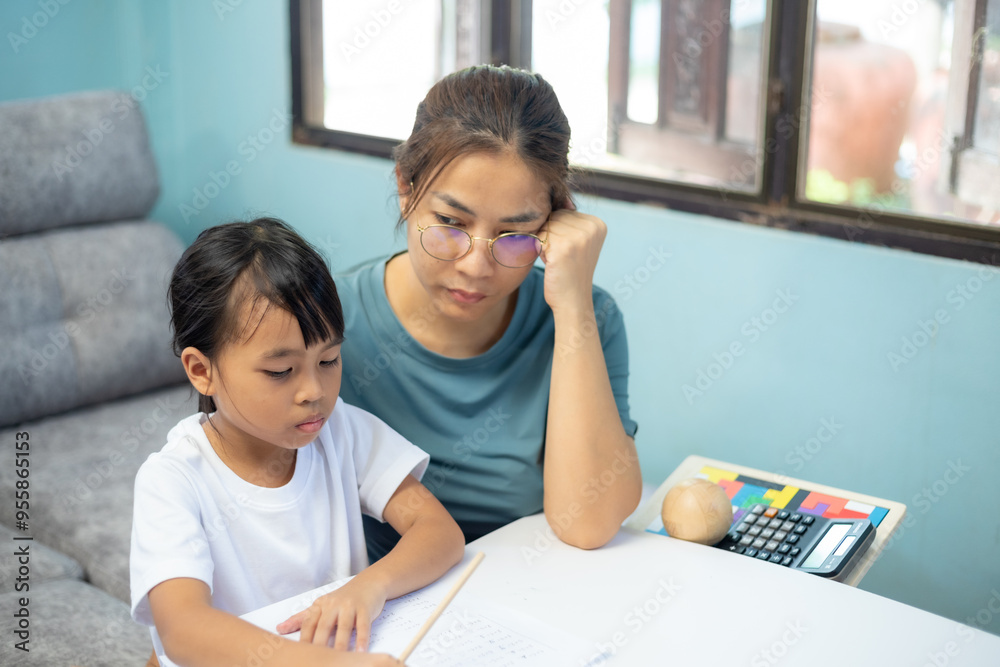 A woman is helping a young girl with her homework.