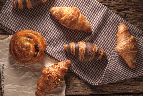 Freshly baked Raisin Danish Pastry and croissants. Arranged on a cloth and parchment paper. photo