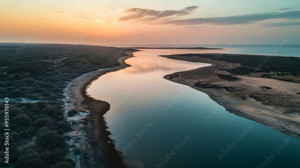 Fototapeta premium The drone captures a tranquil coastal lagoon during sunset, with calm waters reflecting the warm colors of the sky