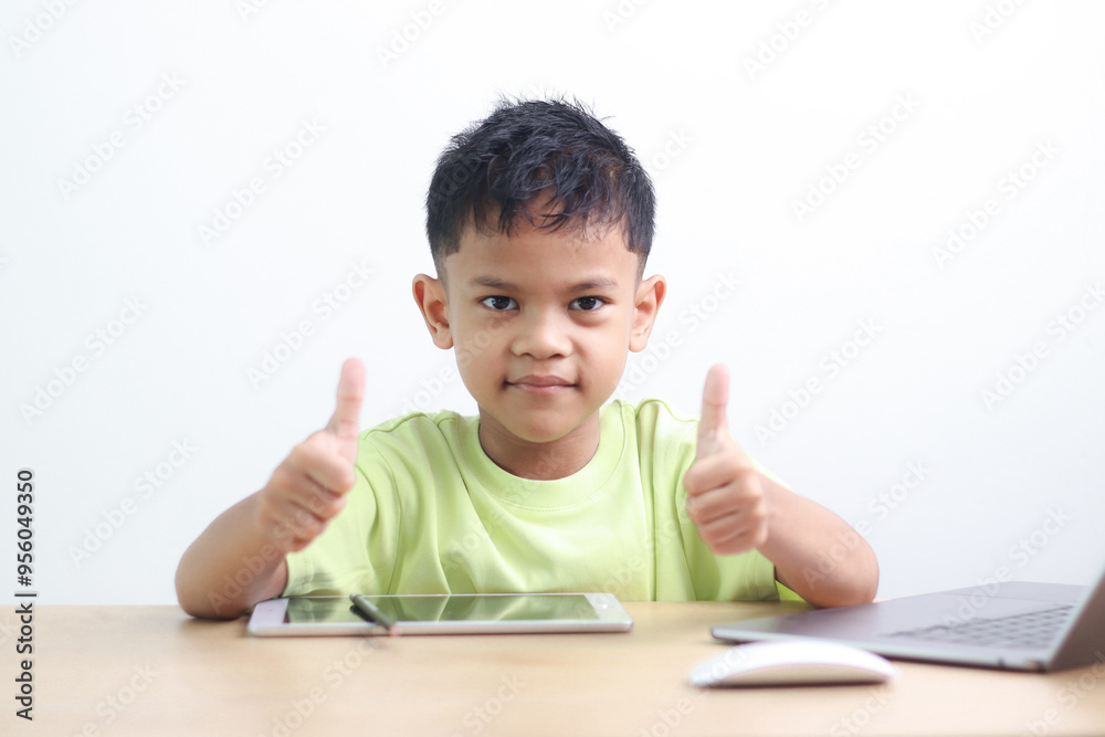 A Happy little asian boy studying online learning class with online video call zoom teacher at home. E-learning or Home schooling education concept. A Happy little asian boy studying online learning class with online video call zoom teacher at home. E-learning or Home schooling education concept.