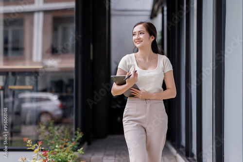 Smiling asian female accountant standing with documents outdoor workplace office