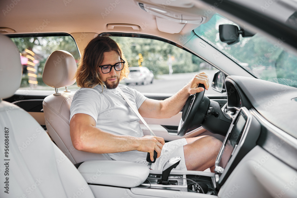 Man in casual attire using gear shift in modern car interior Man in casual attire using gear shift in modern car interior
