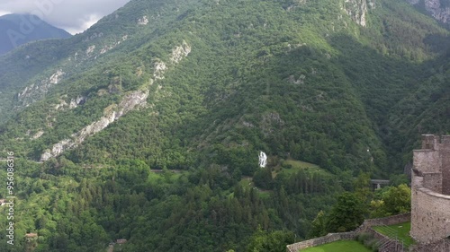 Flight over Castle of Stenico at summer. Rio bianco natural area waterfall in the background. Scenic view of Stenico Castle, a historic fortress in Trento, nestled in the Dolomites. photo