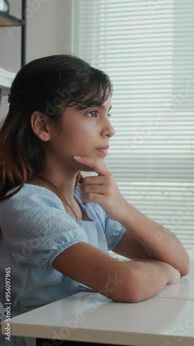 Vertical shot of schoolgirl holding hand on face while practicing pronunciation at speech therapy class photo