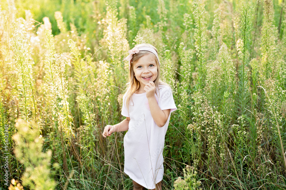 Close up portrait of happy cute little girl in light dress in field of wildflowers at summer sunset. The concept of joy of life, happiness, success, travel. Sunny summer day at sunset. happy childhood