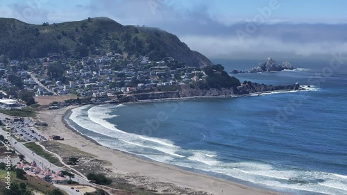 Aerial view of Pacifica State Beach in Pacifica, California, showcasing a beautiful blue sky with a cloud shelf in the background, white sandy beaches, and clear blue water