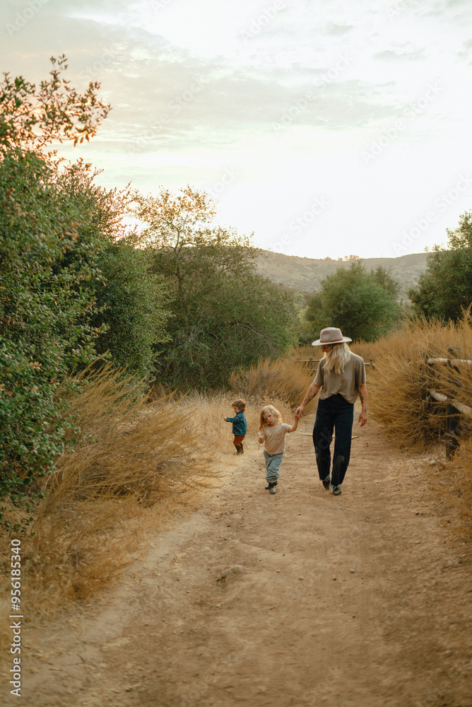 Mom and two children walk down nature trail at sunset Mom and two children walk down nature trail at sunset