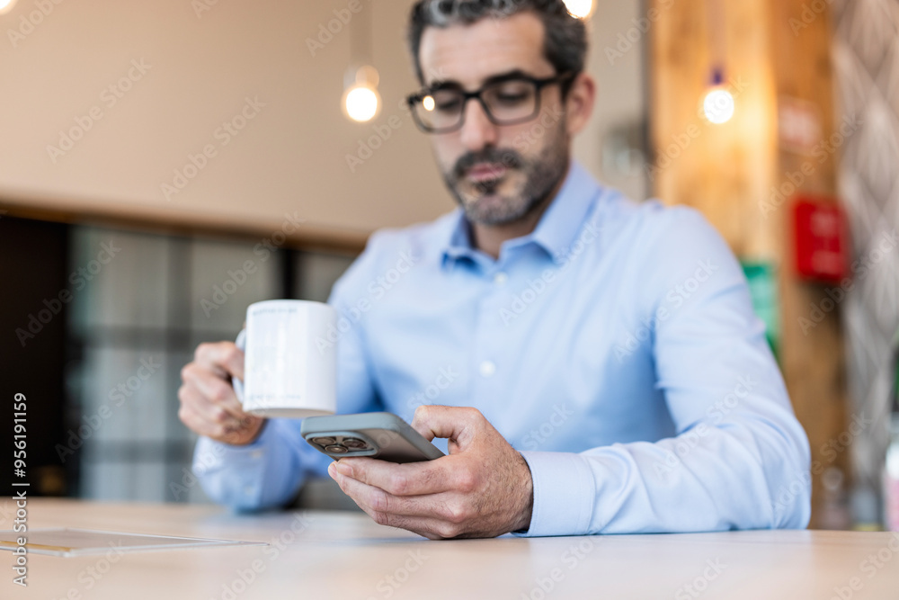 Businessman with coffee cup using smart phone at co working space Businessman with coffee cup using smart phone at co working space
