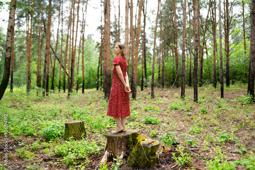 Carefree woman standing on tree stump in forest photo