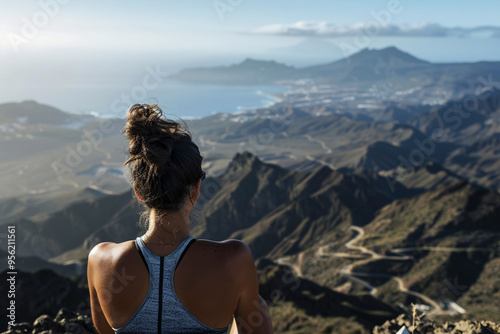 A woman gazing over a vast mountainous landscape, signifying adventure, exploration, and appreciation for nature, set against a backdrop of the sea and distant mountains. photo